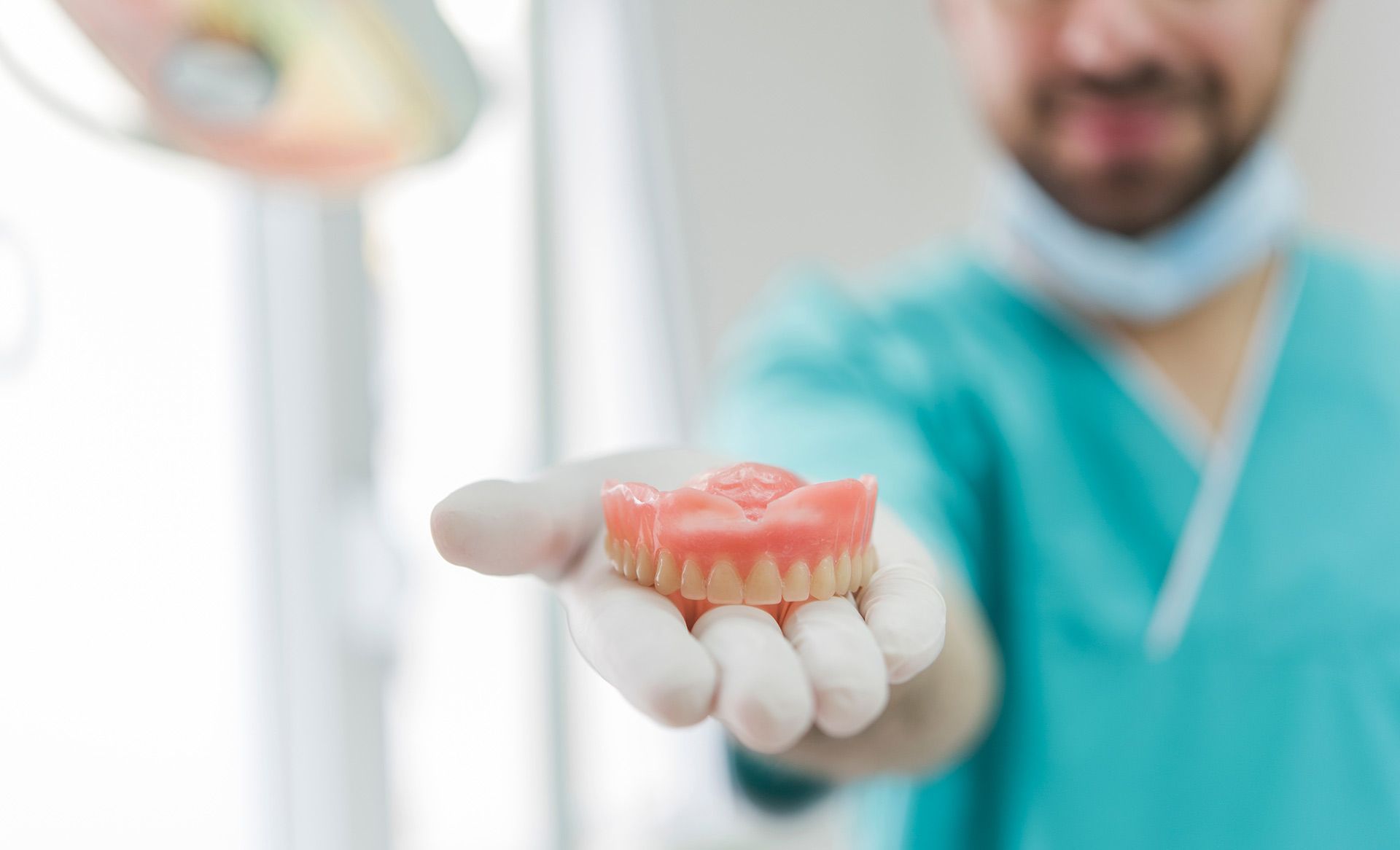 A Dentist Is Holding A Denture In His Hand — Regal's Dental In Emu Park, QLD