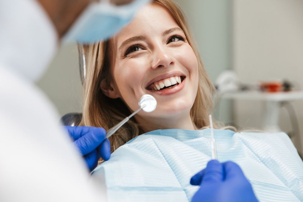 A Woman Is Sitting In A Dental Chair While A Dentist Examines Her Teeth — Regal's Dental In Emu Park, QLD