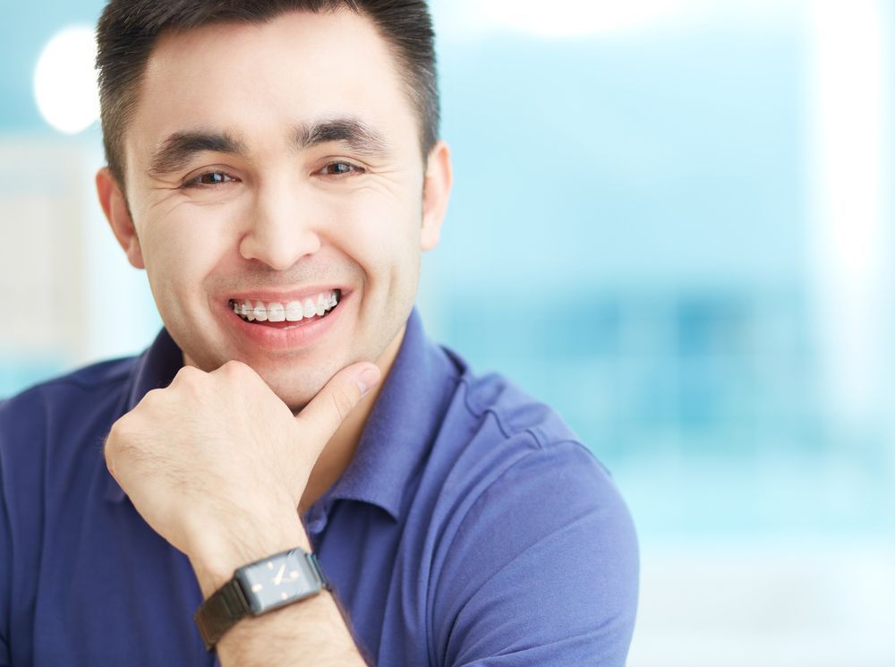 A Man Wearing A Watch Is Smiling With His Hand On His Chin — Regal's Dental In Yeppoon, QLD