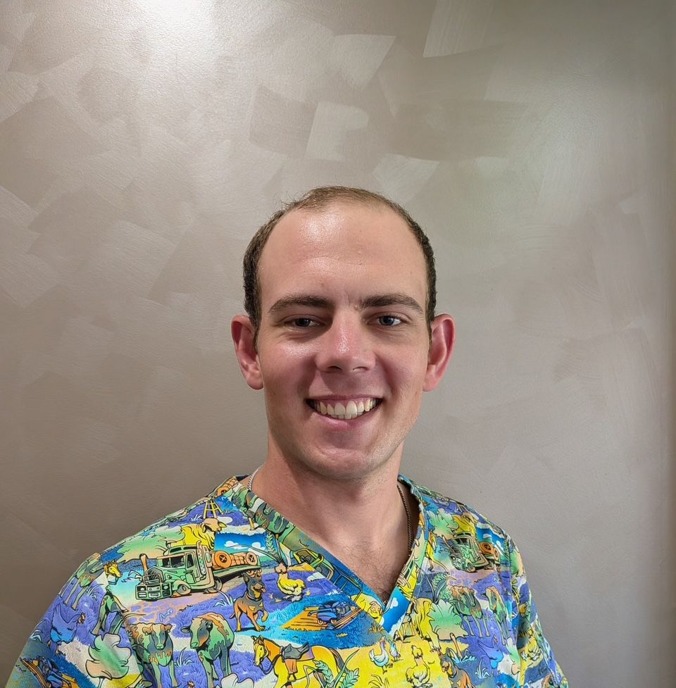 Smiling man in colourful patterned shirt standing against a gray background — Regal's Dental In Yeppoon, QLD