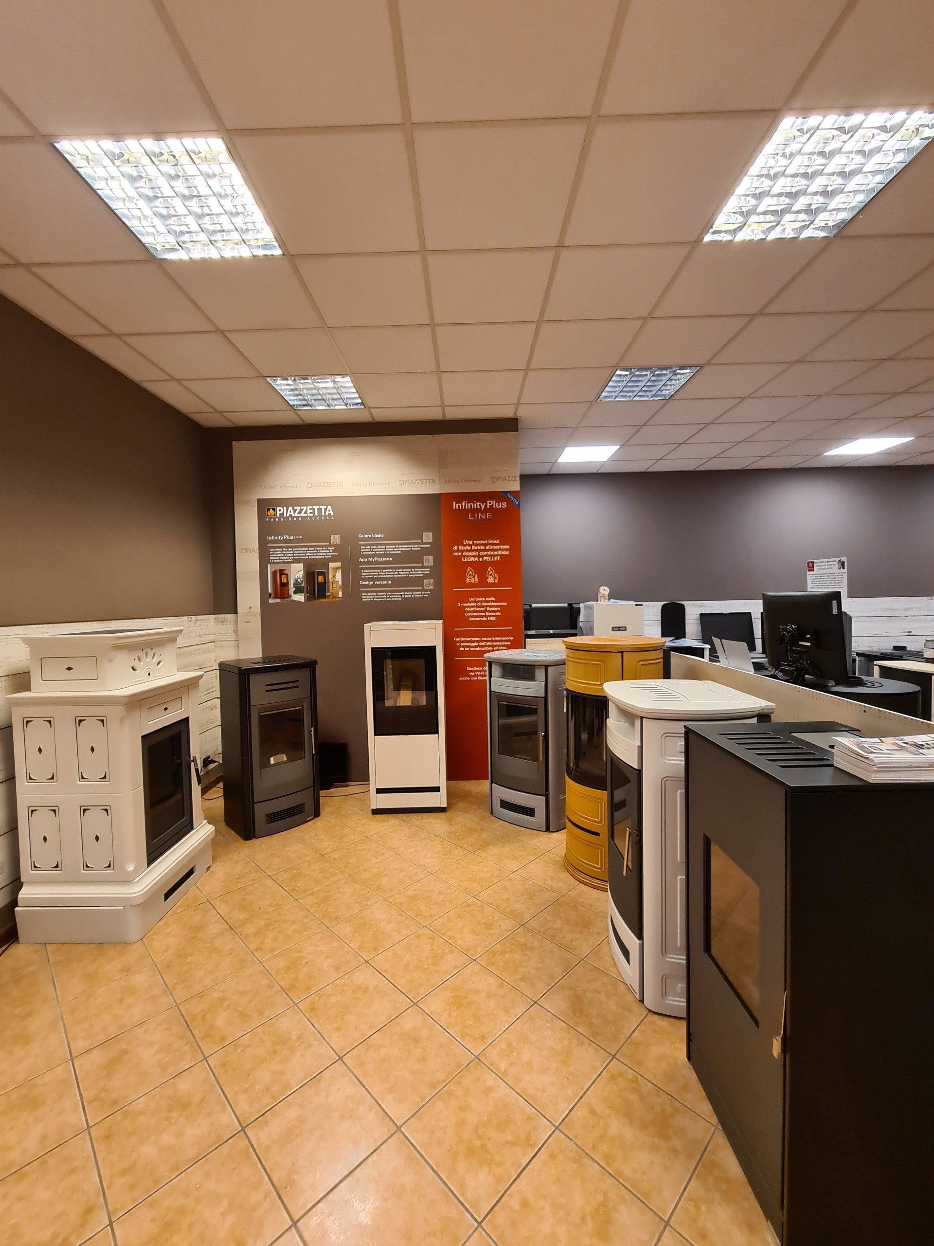 Showroom di elettrodomestici con file di lavatrici, asciugatrici e frigoriferi sotto luci intense del soffitto.