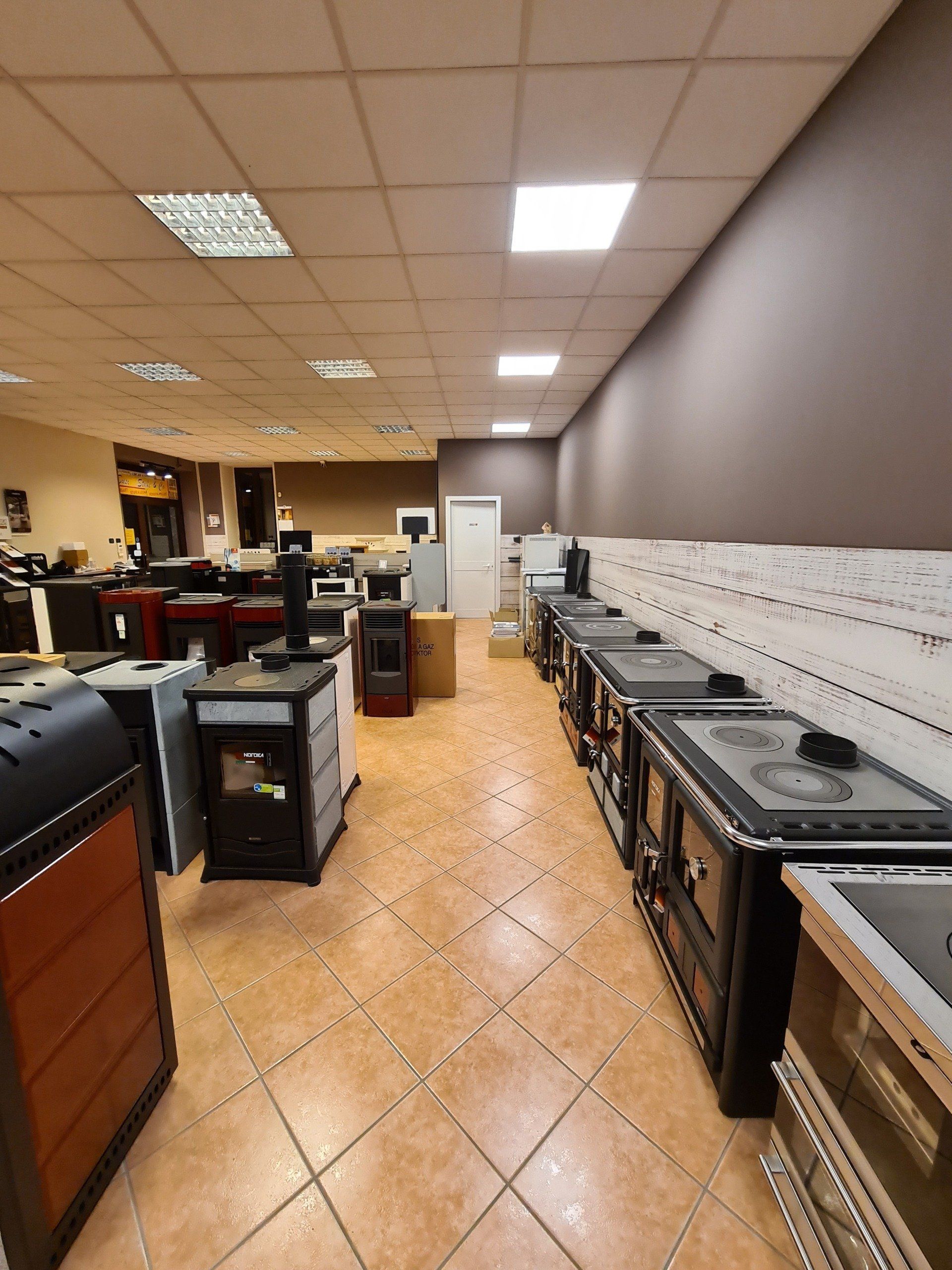 Corridoio del negozio con file di elettrodomestici neri e pavimento piastrellato sotto luci intense del soffitto