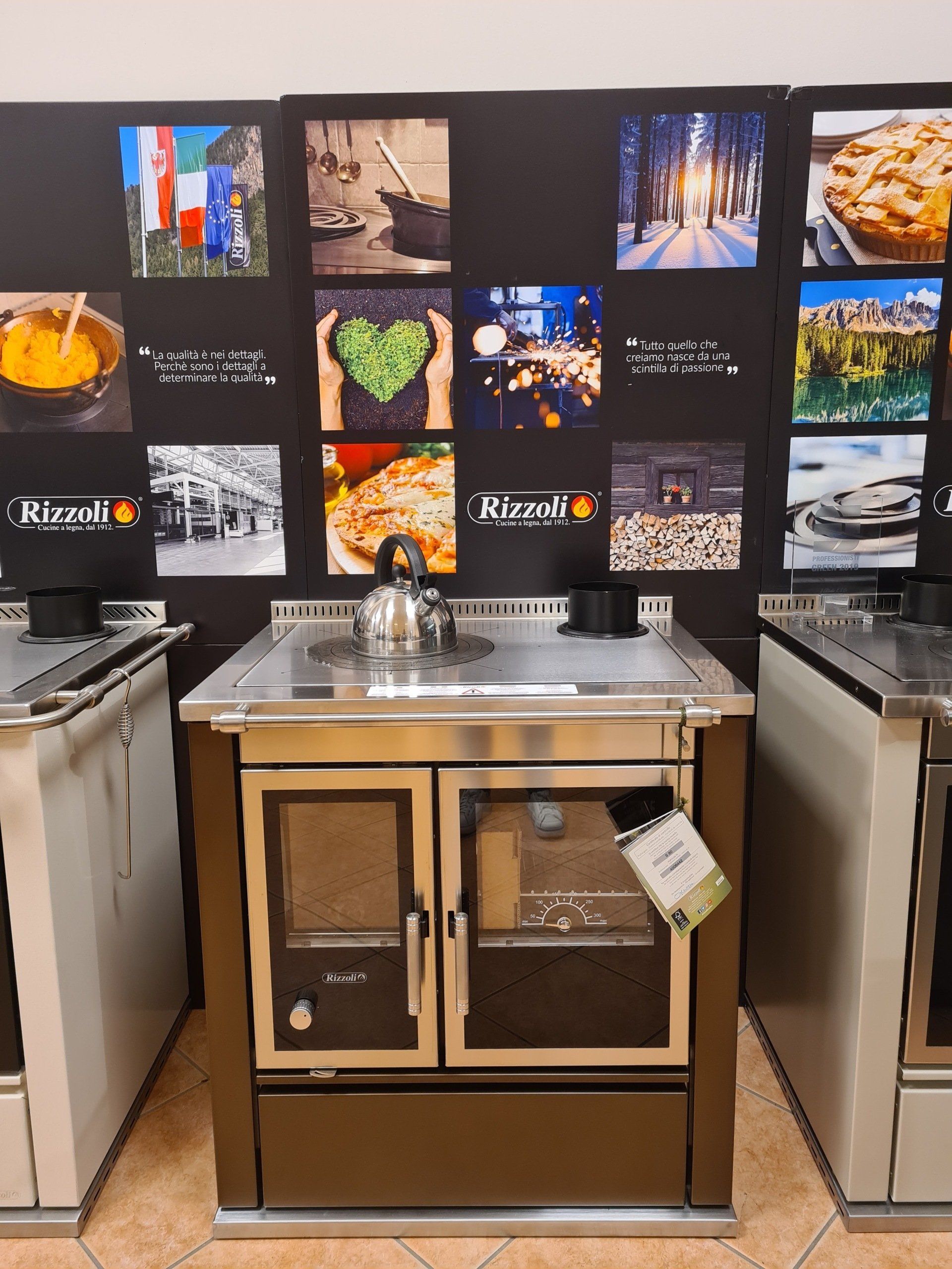 Stazione a buffet per la colazione dell'hotel con banconi in acciaio inox, lavello e parete con piastrelle decorate con foto di cibo e viaggi.