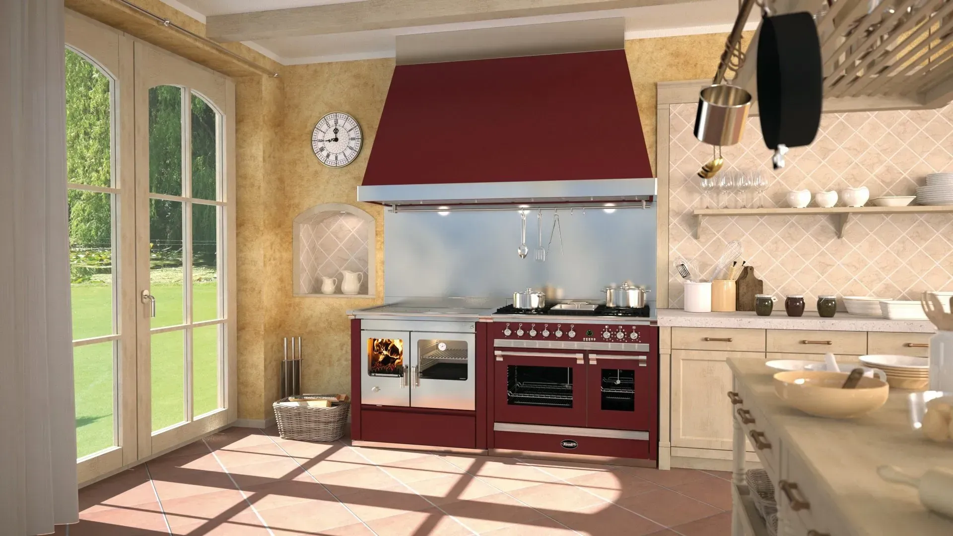 Cucina luminosa con cappa rossa, mobili color crema, pavimento illuminato dal sole e porte finestre che si aprono sul giardino.