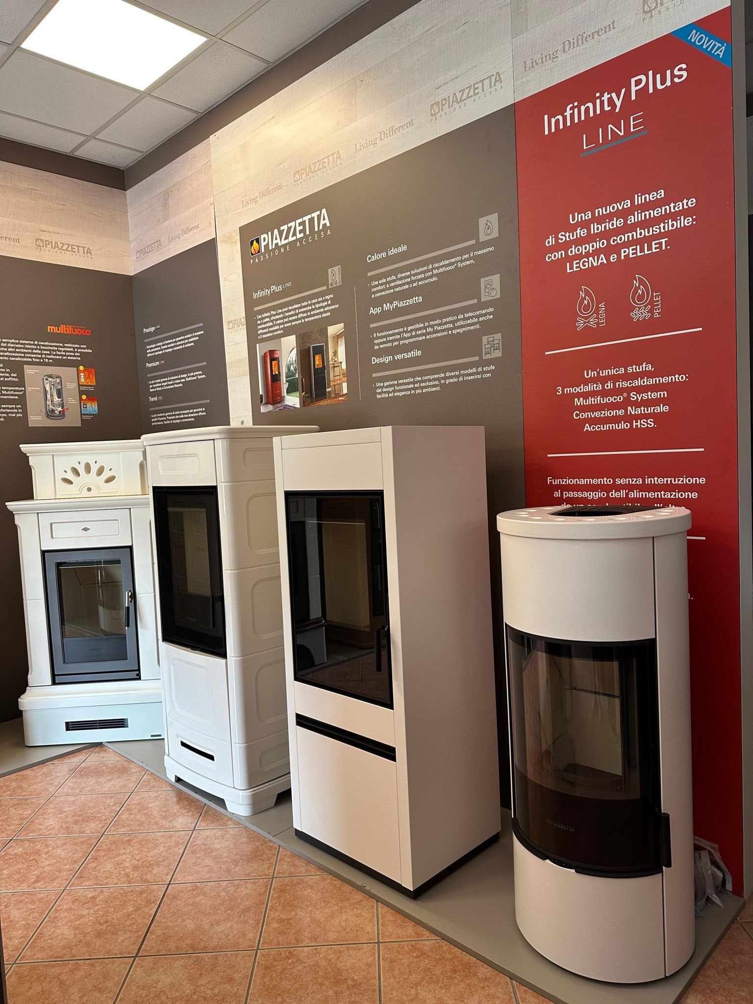 Showroom di elettrodomestici da cucina con fornelli e forni bianchi esposti su una parete scura e insegne rosse