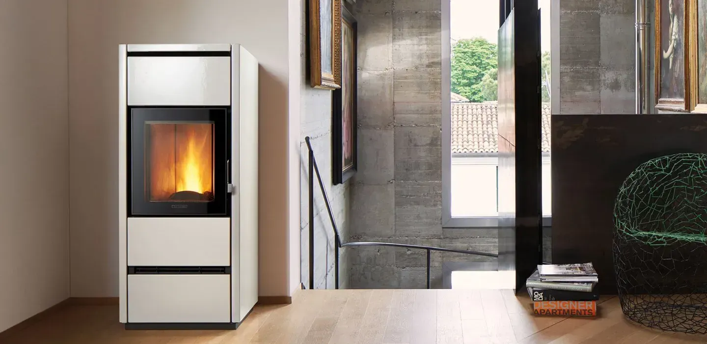 Stufa a pellet moderna di colore bianco con fiamma a vista in un soggiorno contemporaneo.