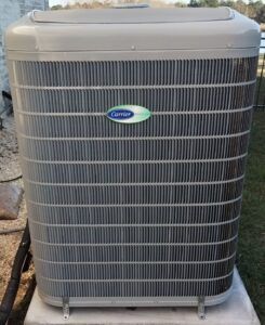 Outdoor gray Carrier air conditioner condenser unit on a concrete pad.