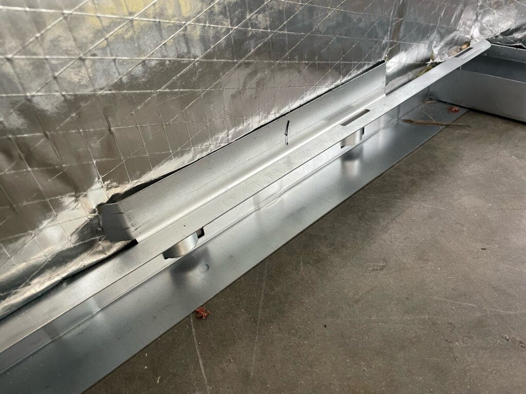 Metal base trim and insulated wall panel along a concrete floor in an industrial interior