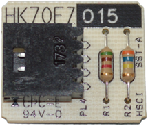 Close-up of a circuit board with a black chip, two resistors, and printed labels on a white background