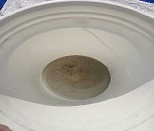 Close-up of a white speaker cone with a dusty center and a thin crack on the rim