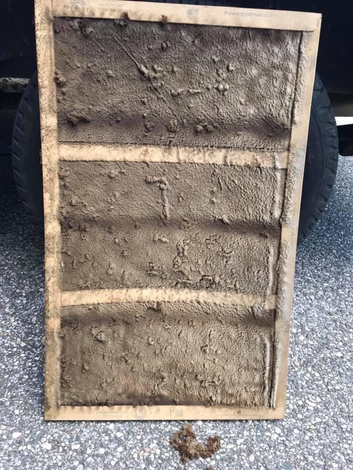 Rectangular wooden frame with three horizontal braces, filled with mud or plaster, leaning upright outdoors