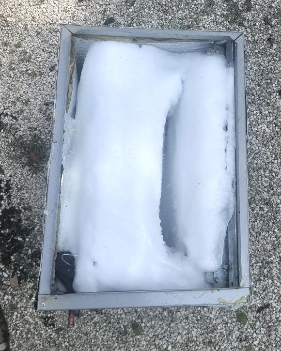 Snow-filled rectangular metal tray on gravel ground