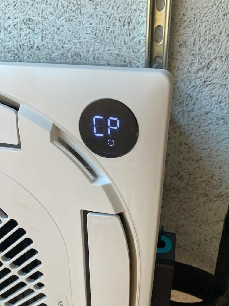 Close-up of an air conditioner control panel showing “CP” on a black circular display.