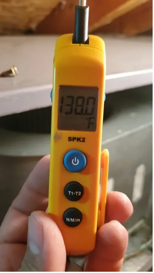 Handheld yellow digital sound meter with black probe, showing a reading of 38.0 in a room