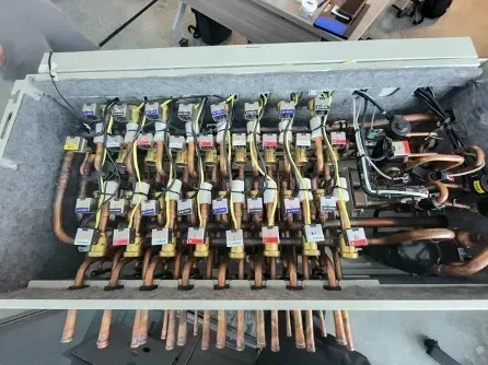Electrical switchgear panel with multiple wires, relays, and copper busbars inside an open metal cabinet