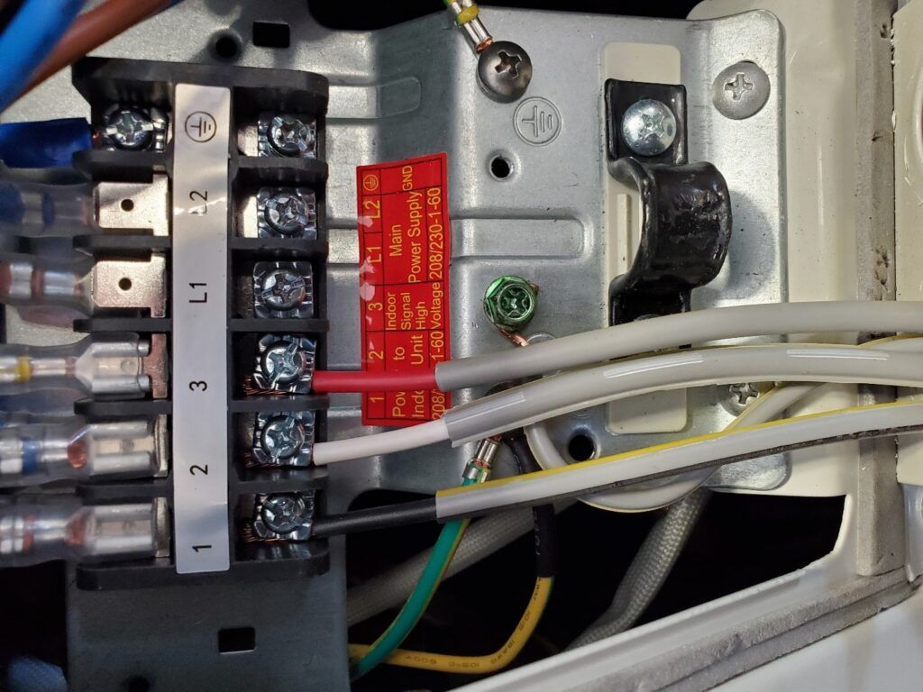 Close-up of an electrical terminal block with numbered screws and connected wires inside a device.