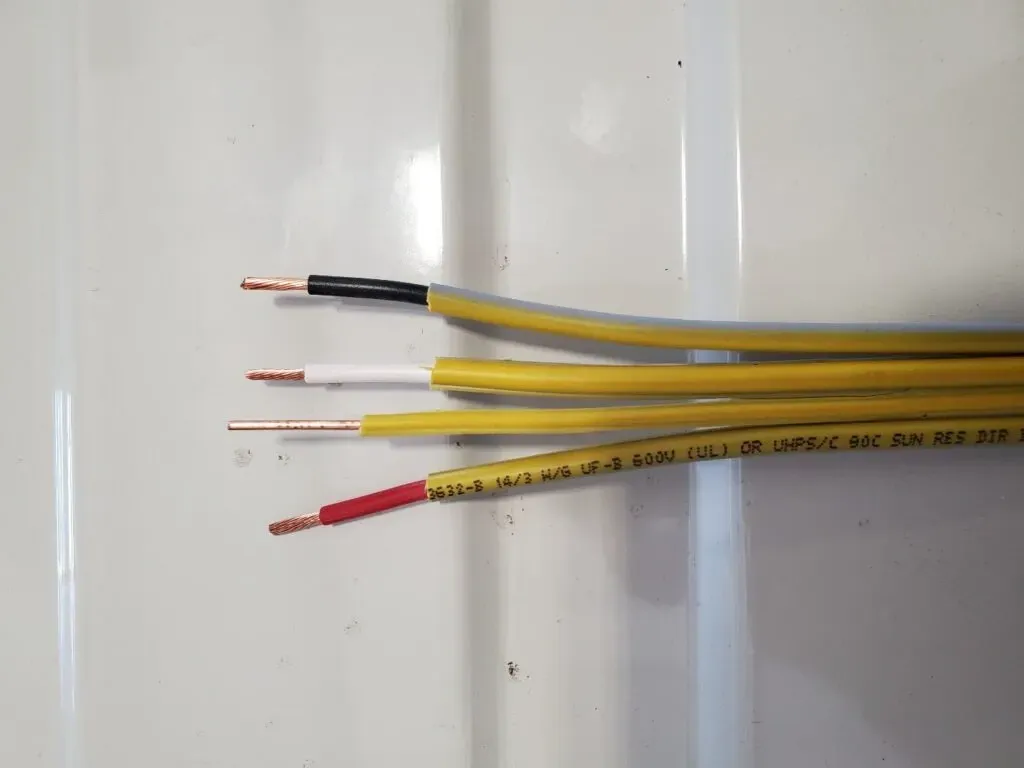 Four stripped electrical wires with colored insulation ends on a white surface.
