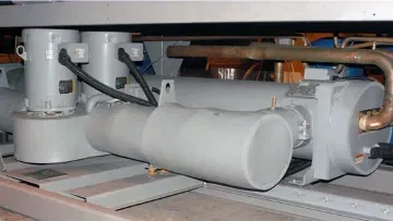 Industrial machinery with a large white cylindrical tank and connected piping in a factory setting