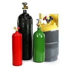 Colorful gas cylinders and industrial tanks with valves on top, including red, black, green, and gray containers.