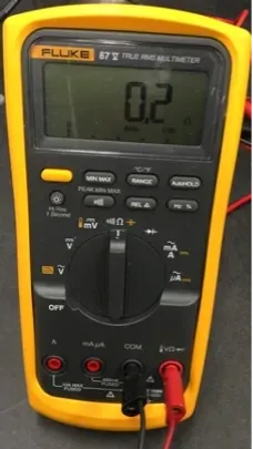 Yellow Fluke digital multimeter showing 0.2 on the display, with red and black probes plugged in.