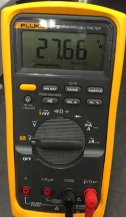 Yellow digital multimeter displaying 27.66, with black dial and red probe plugged in on the right
