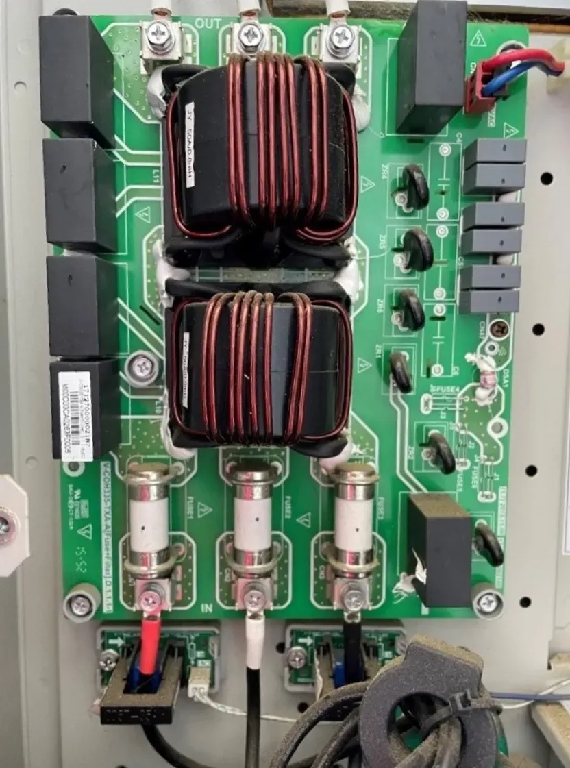 Green circuit board with two large copper coils and multiple electronic components mounted inside a device