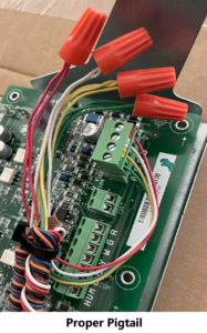 Electrical wiring with orange wire nuts on a green circuit board inside a cardboard box