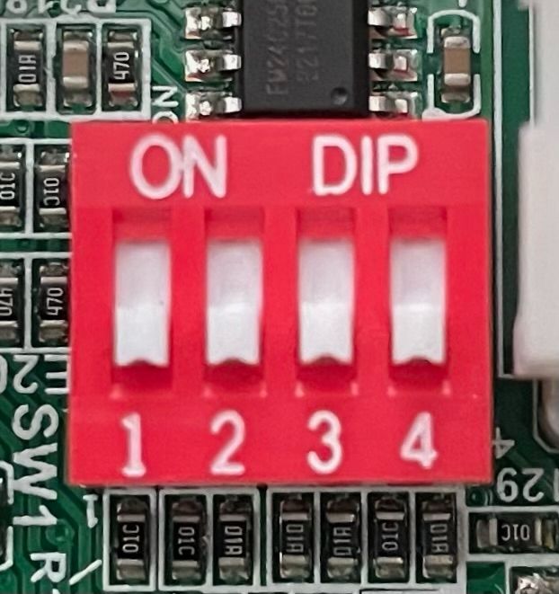 Close-up of a red 4-position DIP switch on a circuit board, labeled ON and 1–4.