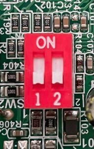 Red two-position DIP switch on a circuit board labeled ON and 1 2