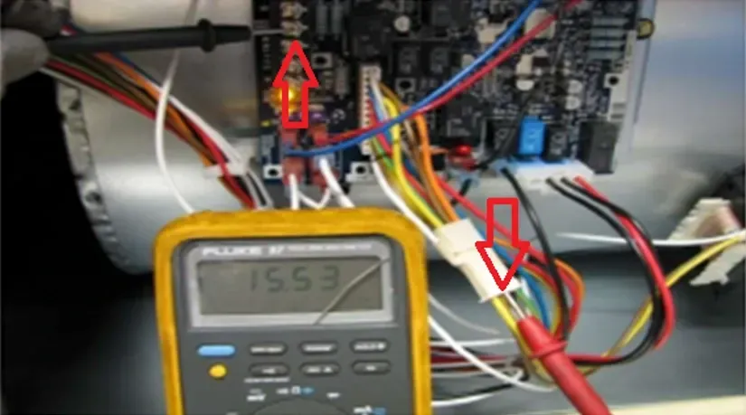 Multimeter probing a circuit board with red arrows marking wires inside an electronics enclosure