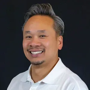 Smiling man in a white polo shirt against a dark background