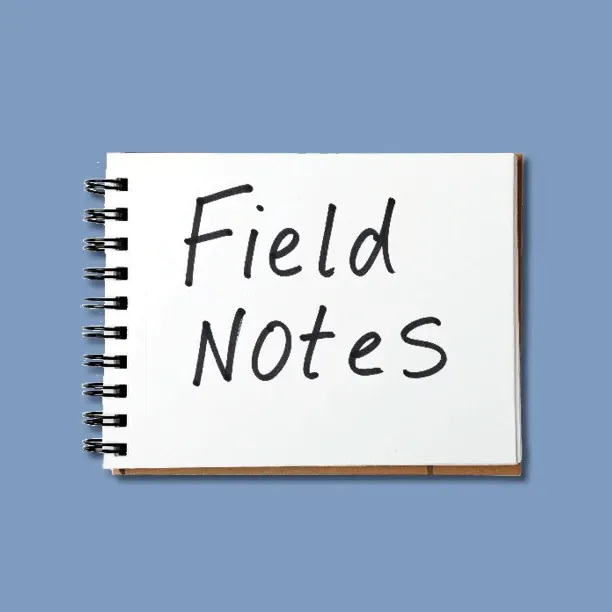 Field notes written on a white spiral notebook against a blue background