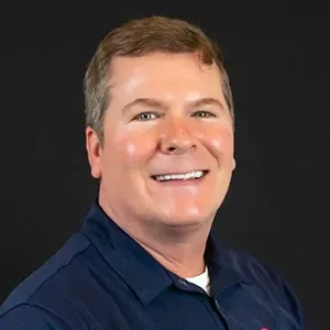 Smiling man in a navy shirt against a dark background