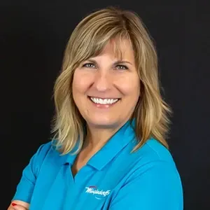 Smiling woman in a bright blue shirt against a dark background