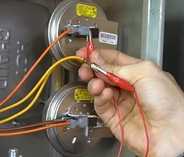 Hand connecting red wire alligator clips to electrical terminals on two round metal components