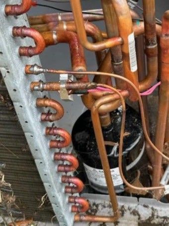 Copper HVAC refrigeration lines and wiring inside an open unit, with a black compressor visible.