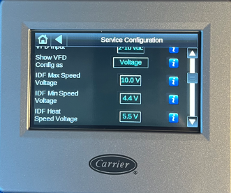 Carrier HVAC touchscreen showing service configuration settings and voltage values on a gray control panel.