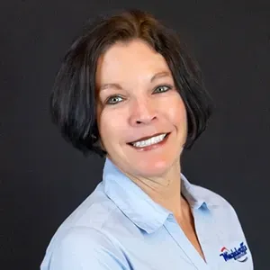 Smiling woman in a light blue shirt against a dark background