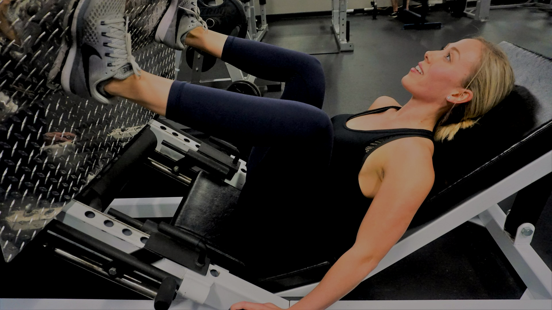 A woman is using a leg press machine in a gym.