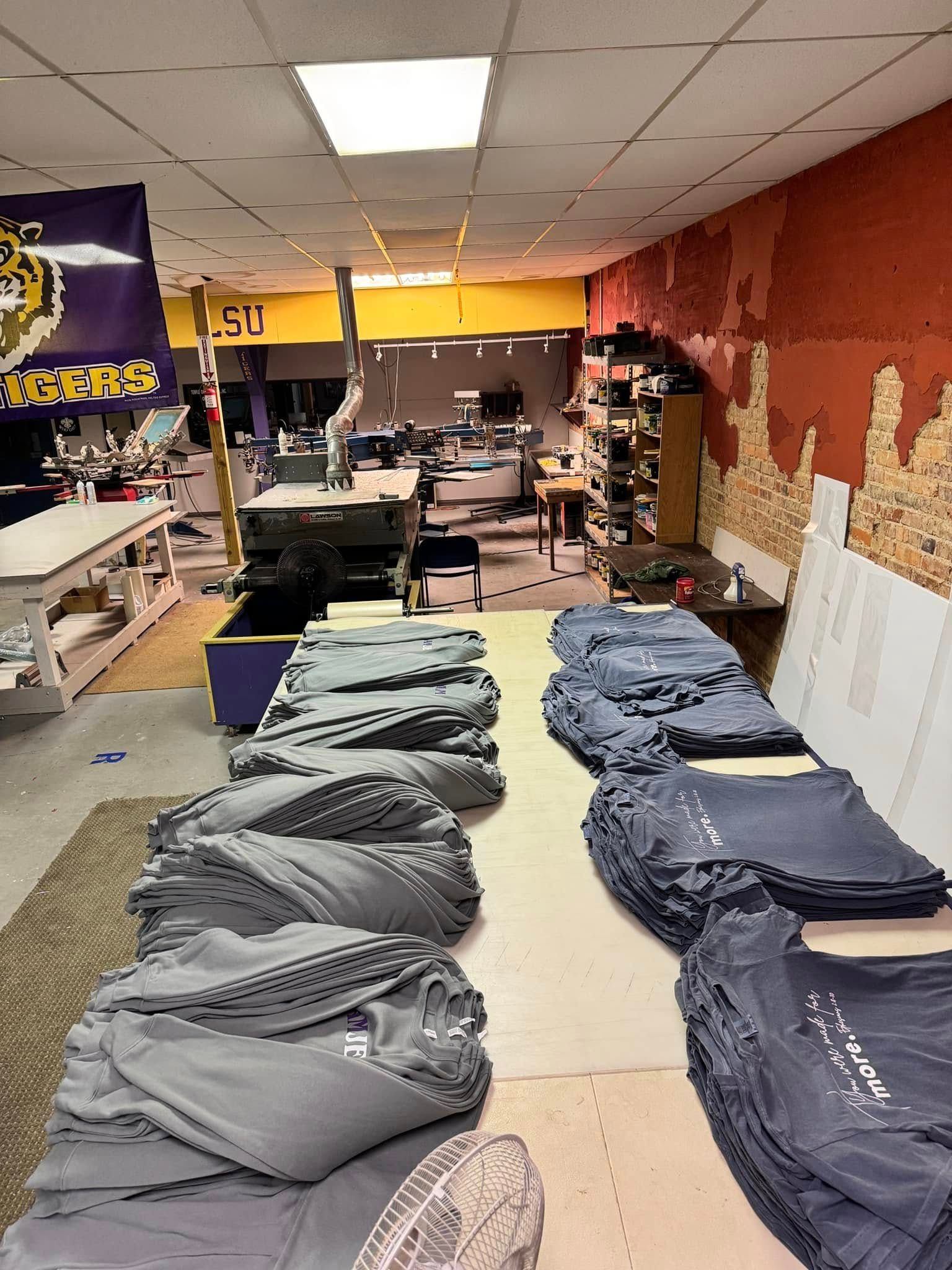 A bunch of shirts are sitting on a table in a room.
