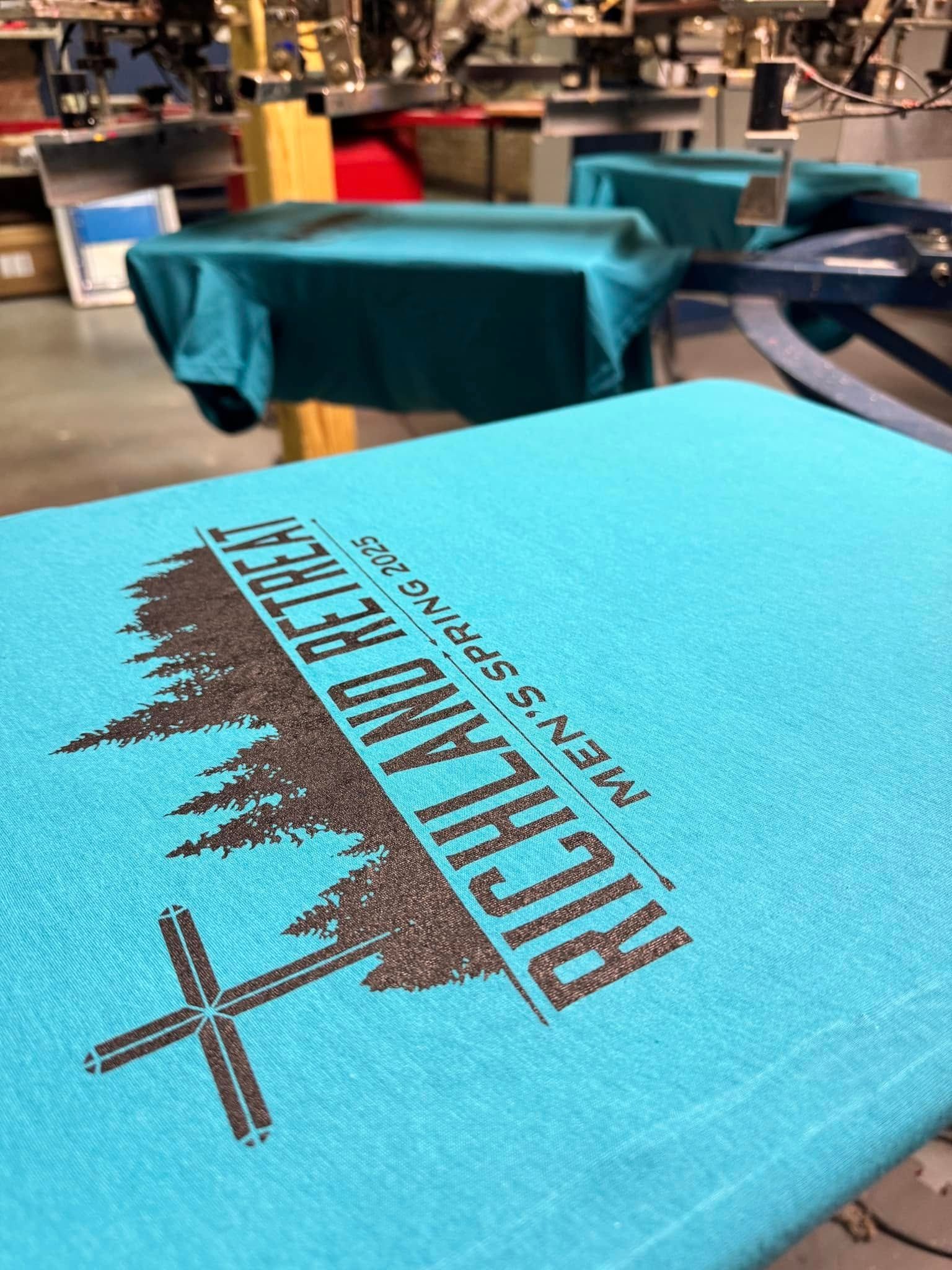 A blue t-shirt with a cross on it is sitting on top of a table.
