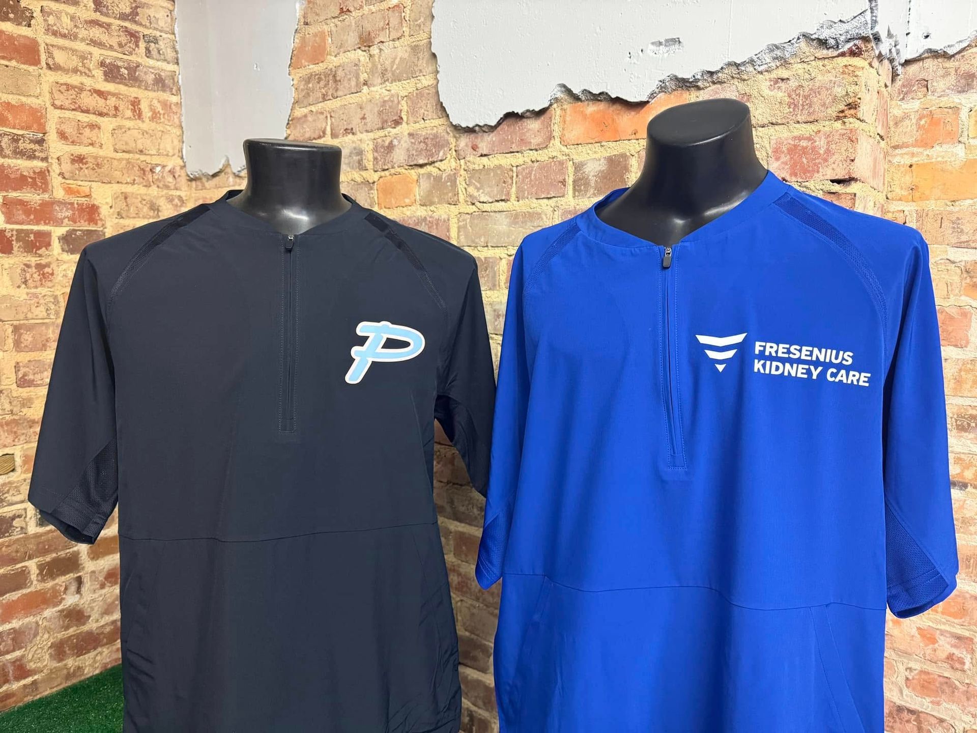 Two shirts are sitting on a mannequin in front of a brick wall.