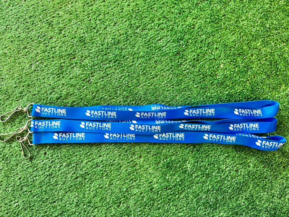 Three blue lanyards are sitting on top of a lush green field.