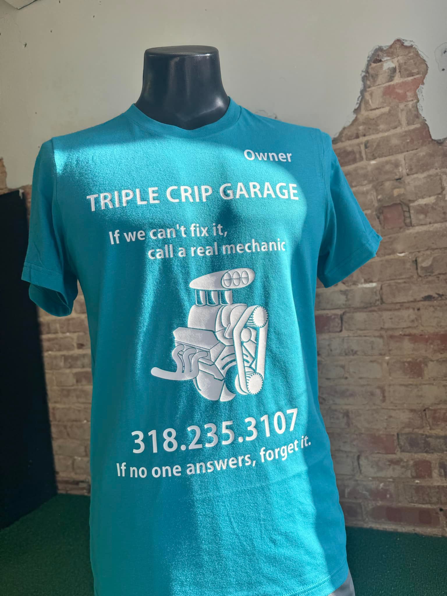 A blue t-shirt is on a mannequin in front of a brick wall.