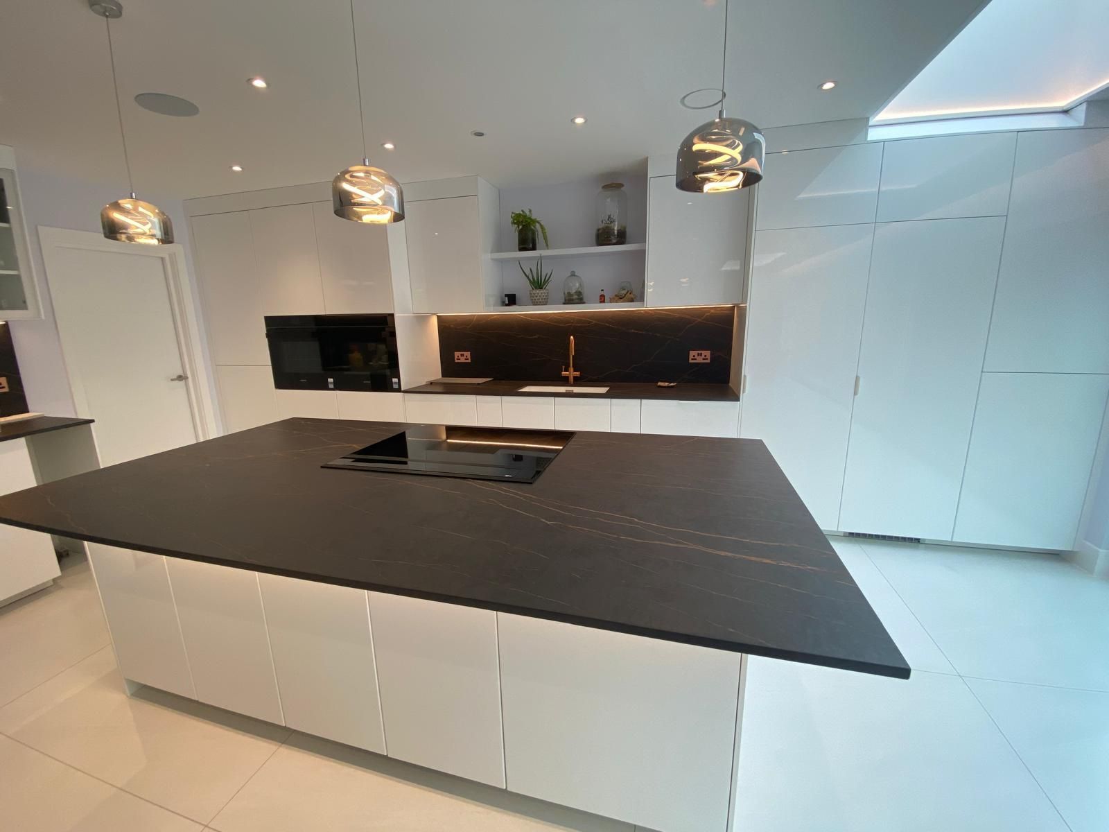 Modern white kitchen with a large dark island and pendant lights.