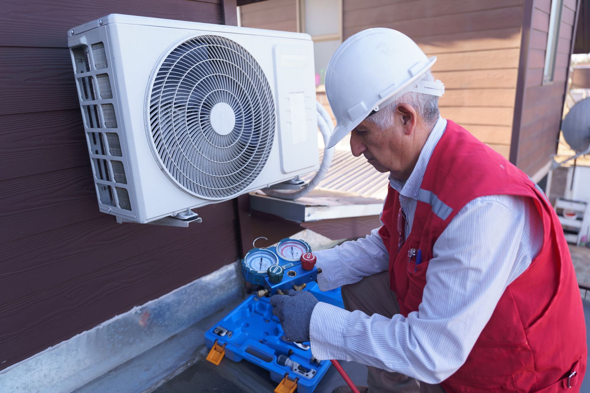 A senior HVAC technician is checking unit pressure during a routine HVAC maintenance service.