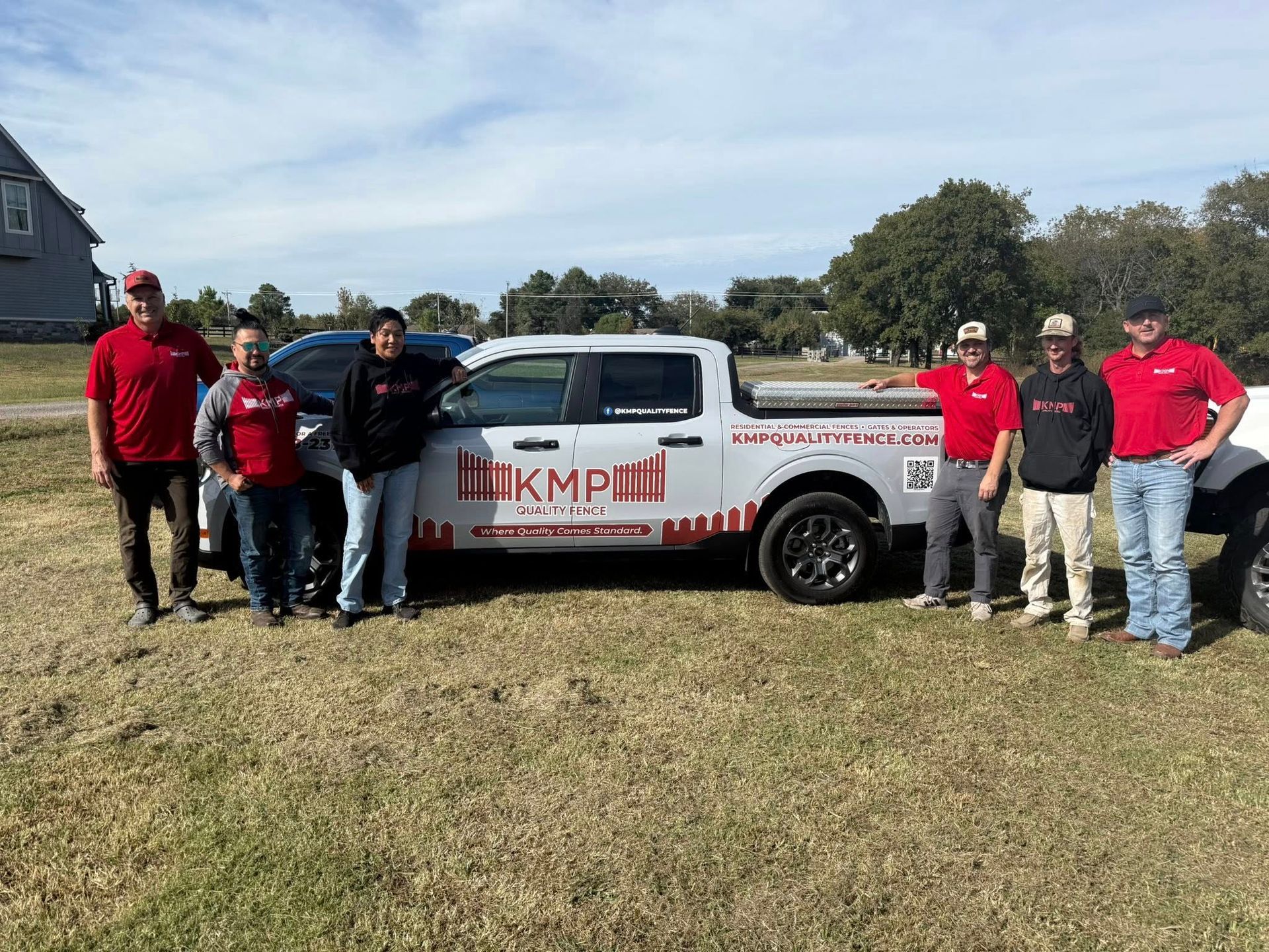 Group posing beside a white pickup truck with red company graphics in a grassy field