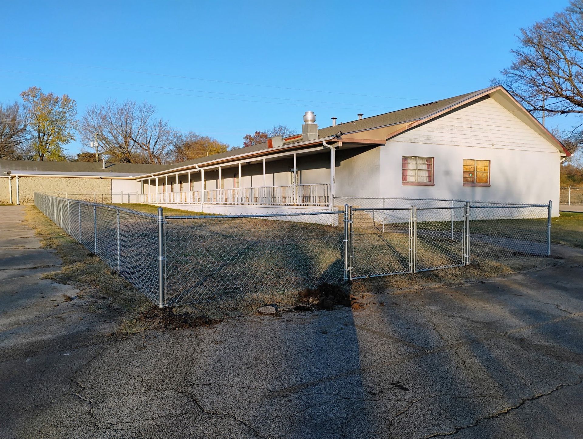 Single-story white building behind a chain-link fence on a sunny day