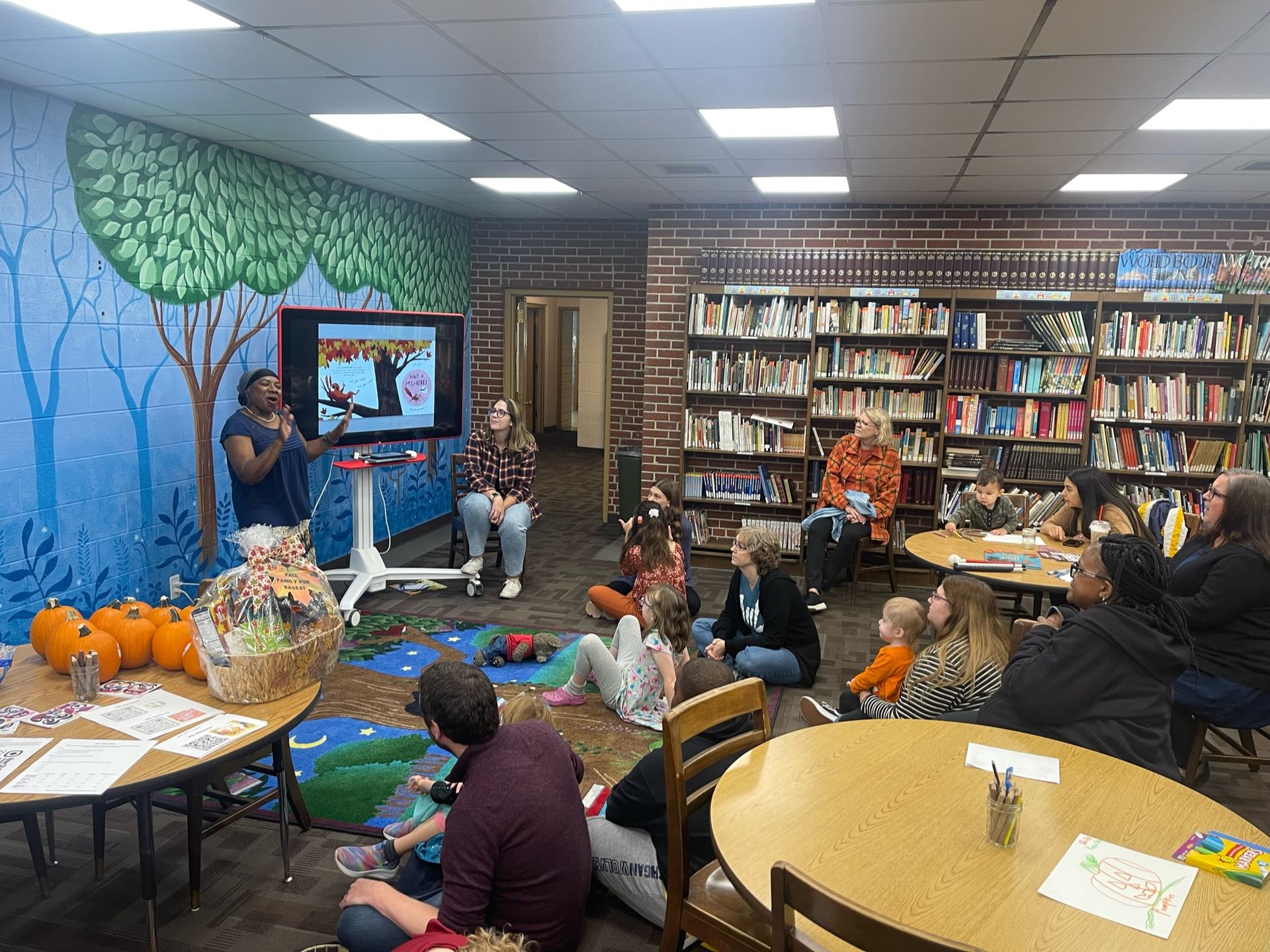 A group of people are sitting around tables in a library.