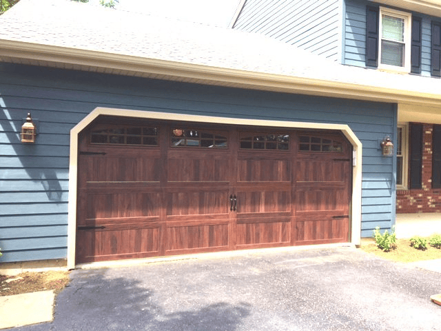 Two-car wooden garage door on a blue house exterior in sunlight